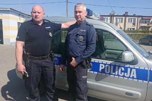 Dwóch policjantów stojących na tle radiowozu