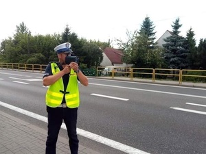 Policjant stoi z ręcznym miernikiem prędkości i mierzy prędkość
