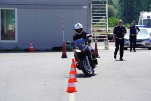 Kierujący służbowym motocyklem omija przeszkody na torze