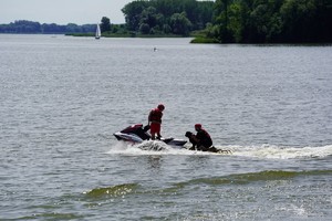 Dwóch ratowników i pies płyną na skuterze wodnym