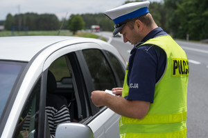 Policjant kontroluje dokumenty samochodu