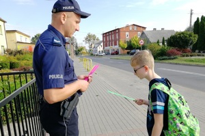 Policjant daruje opaskę odblaskową uczniwowi