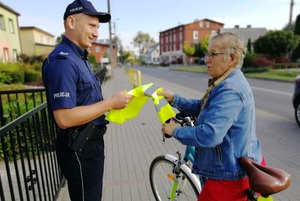 Policjant daje kamizelkę odblaskową rowerzystce