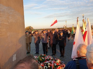 Delegacja mundurowych salutuje pod pomnikiem