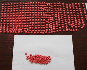 Zabezpieczone tabletki ecstazy rozłożone na stole.