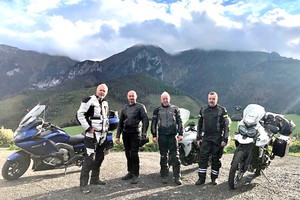 Grupa motocyklistów na tle gór.