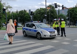 Skrzyżowanie ulic. Policjanci ruchu drogowego kierują blokują przejazd w ramach zorganizowanego objazdu.