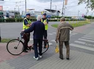Skrzyżowanie ulic. Policjanci ruchu drogowego rozmawiają z rowerzystą.