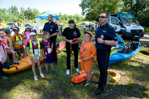 dwaj policjanci i ratownik opowiadają zgromadzonym dzieciom jak spędzać bezpiecznie czas na wodzie oraz jak wzywać pomoc