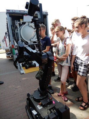 Uczniowie oglądają zdalnie sterowanego robota służącego do przenoszenia niebezpiecznych ładunków.
