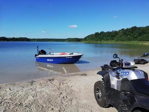 Zwodowana łódź policyjna oraz policyjny quad zaparkowany na nabrzeżu.