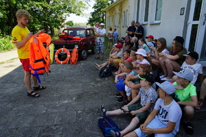 ratownik WOPR pokazuje dzieciom kamizelkę ratunkową
