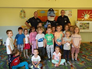 Zdjęcie grupowe policjantów z dziećmi w sali przedszkolnej.