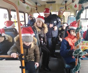 Policjant w czapce Mikołaja wśród dzieci u autobusie.