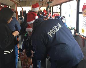Policjant rozmawia z dzieckiem w autobusie i wręcza mu słodki podarunek.